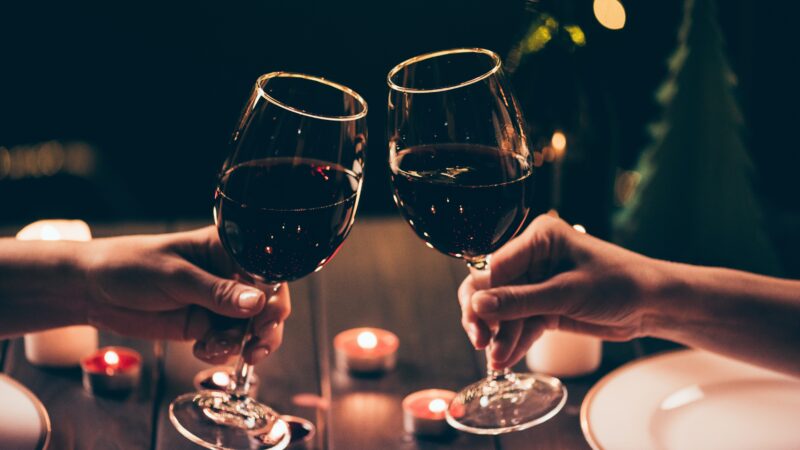 Copas de vino chocando en una cena a la luz de las velas