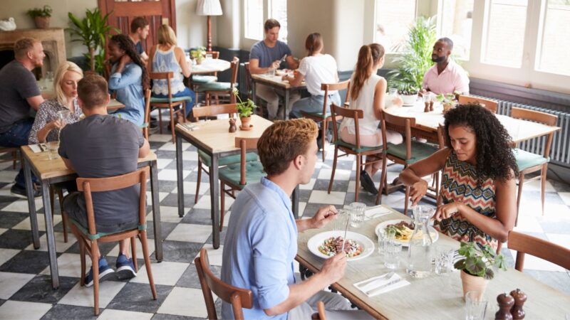 Clientes disfrutando de sus alimentos en un restaurante, ejemplo de cómo la adaptación de menús responde a las preferencias de los consumidores.
